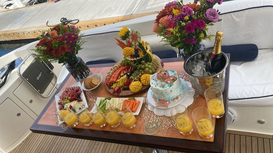 Party table on a yacht with flowers, fruit, a cake and champagne