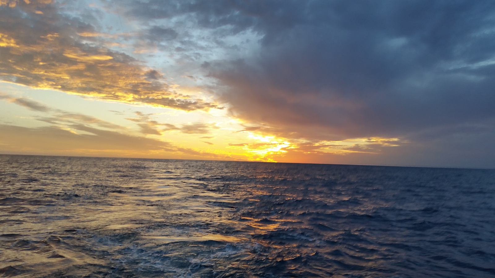 Sunset breaking through clouds over a calm Caribbean sea