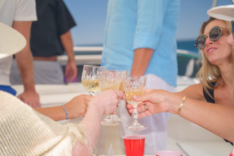Guests raising champagne glasses in a toast on a sunny yacht deck
