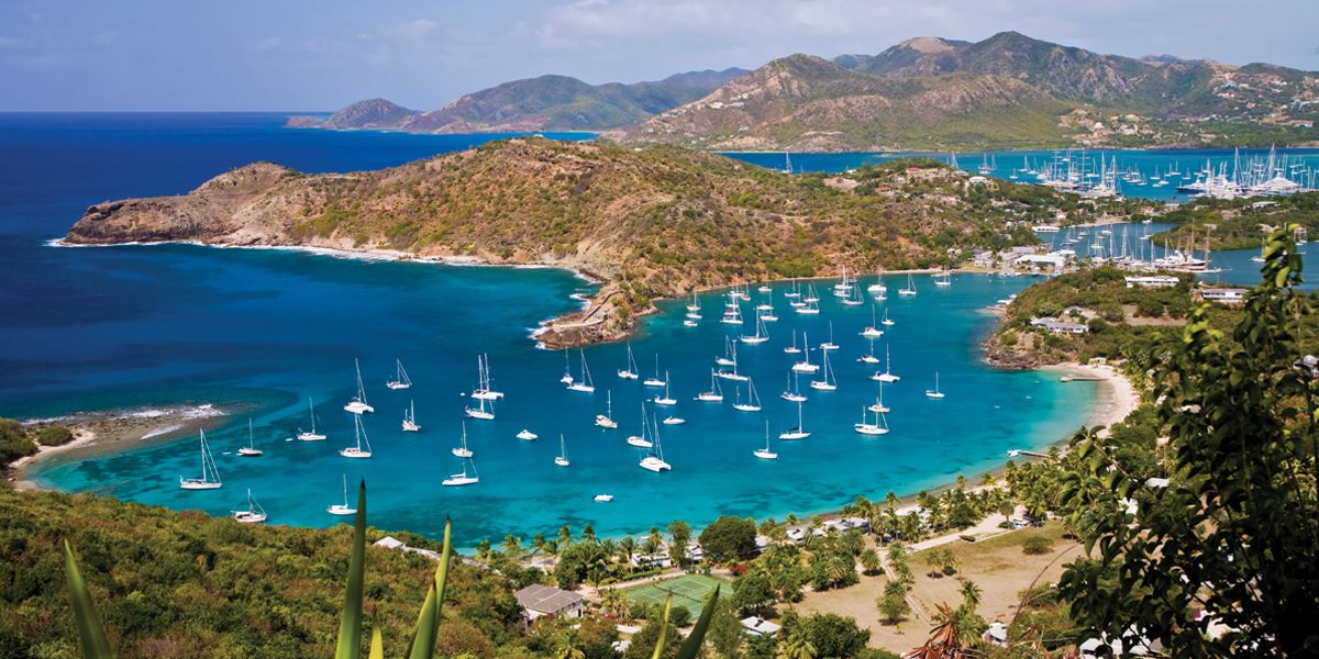View over English Harbour, Antigua, with sailing yachts anchored in a turquoise bay below green hills