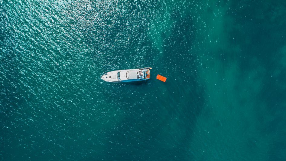 Aerial view of a white motor yacht at anchor in clear turquoise water