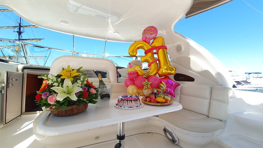 Birthday balloons, flowers and a cake arranged in the cockpit of a yacht