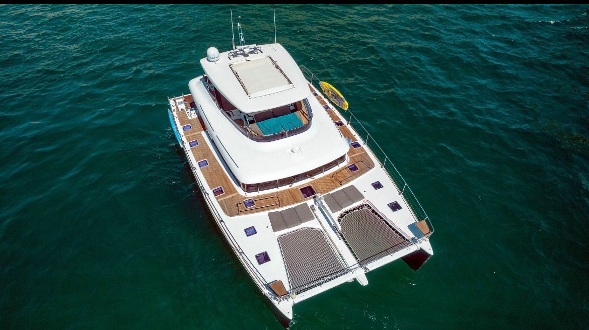 Aerial view of a power catamaran at anchor in deep green water