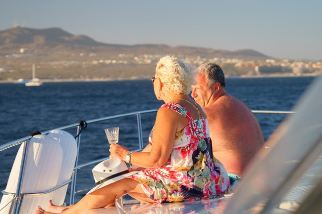 Couple sitting together on a yacht's deck with drinks, looking out over the water