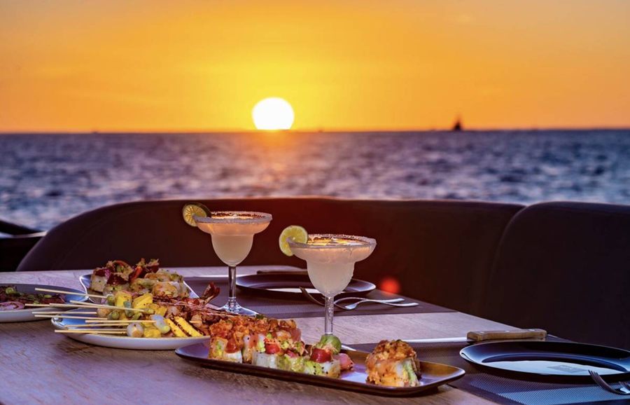 Margaritas and appetizers on a yacht table as the sun sets over the sea